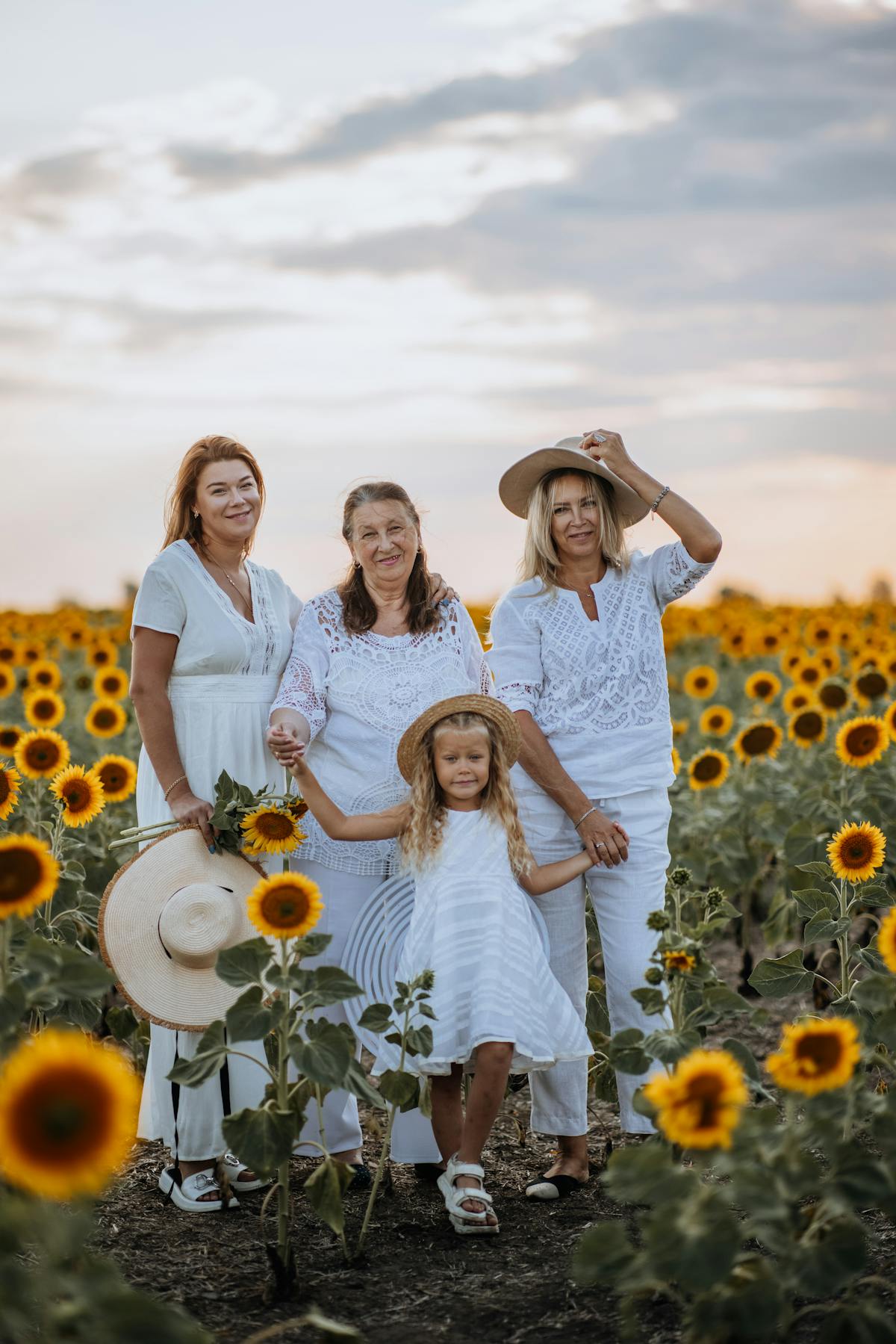 Familie steht gemeinsam in einem Sonnenblumenfeld bei Sonnenuntergang