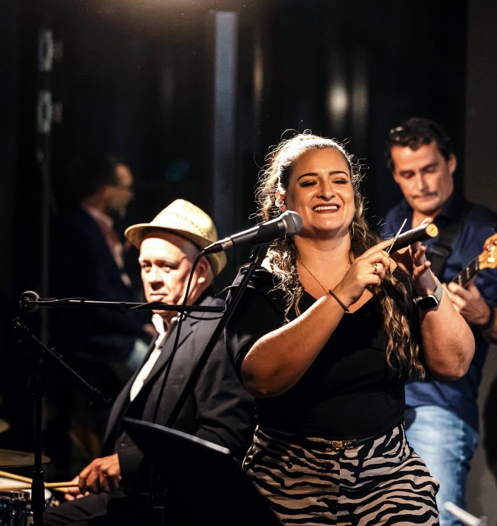 Sängerin der Havana-Night-Live-Band mit Clave auf der Bühne, im Hintergrund Schlagzeuger und Gitarrist