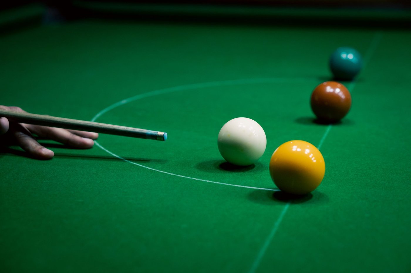 Queue zielt auf die weiße Kugel auf einem grünen Snookertisch