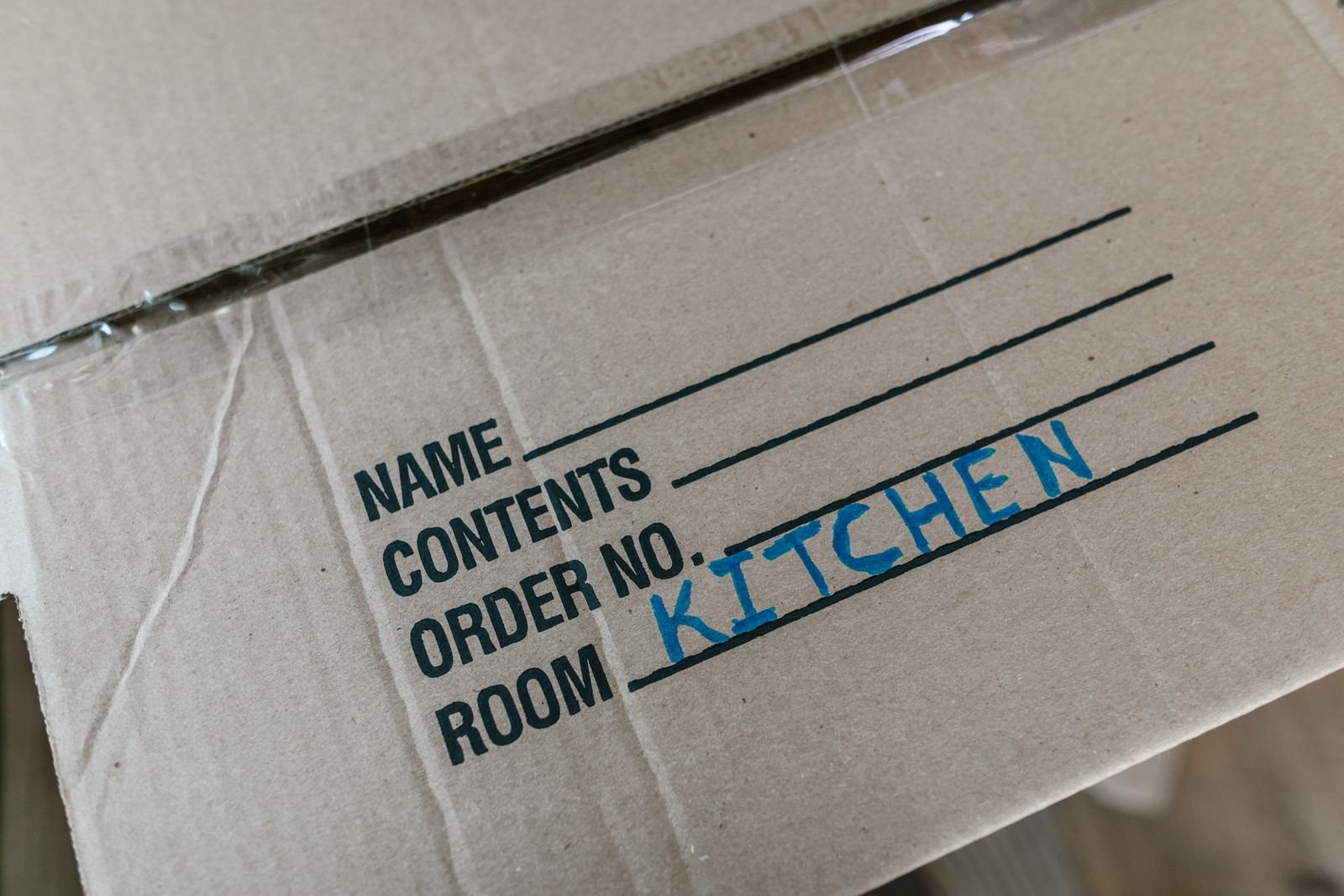 Beschrifteter Umzugskarton beim Packen